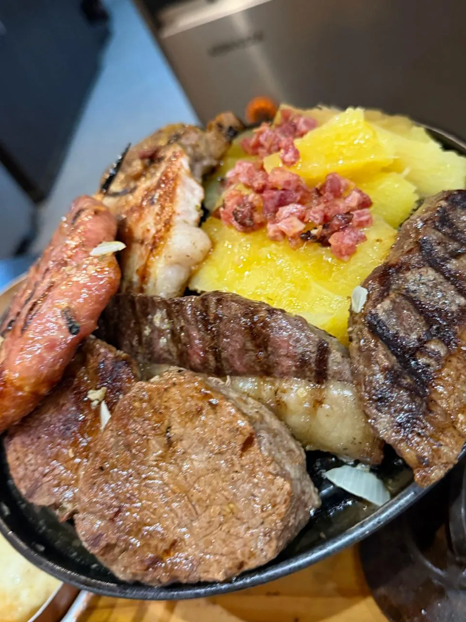 Cortes de carne vermelha grelhados na chapa com linguiça e acompanhamentos
