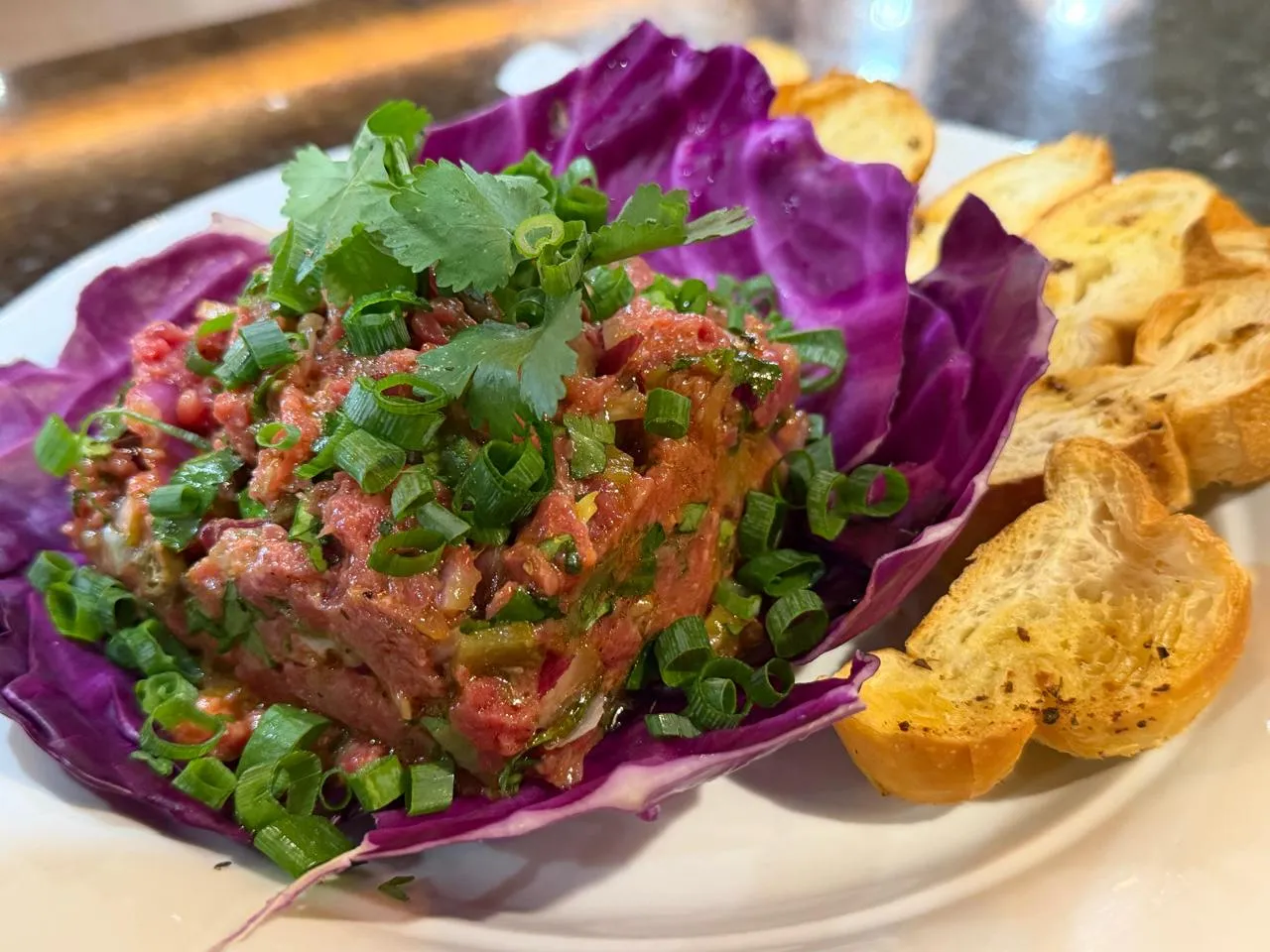 Entrada de carne — Carne temperada com cebolinha e coentro, servida com torradas