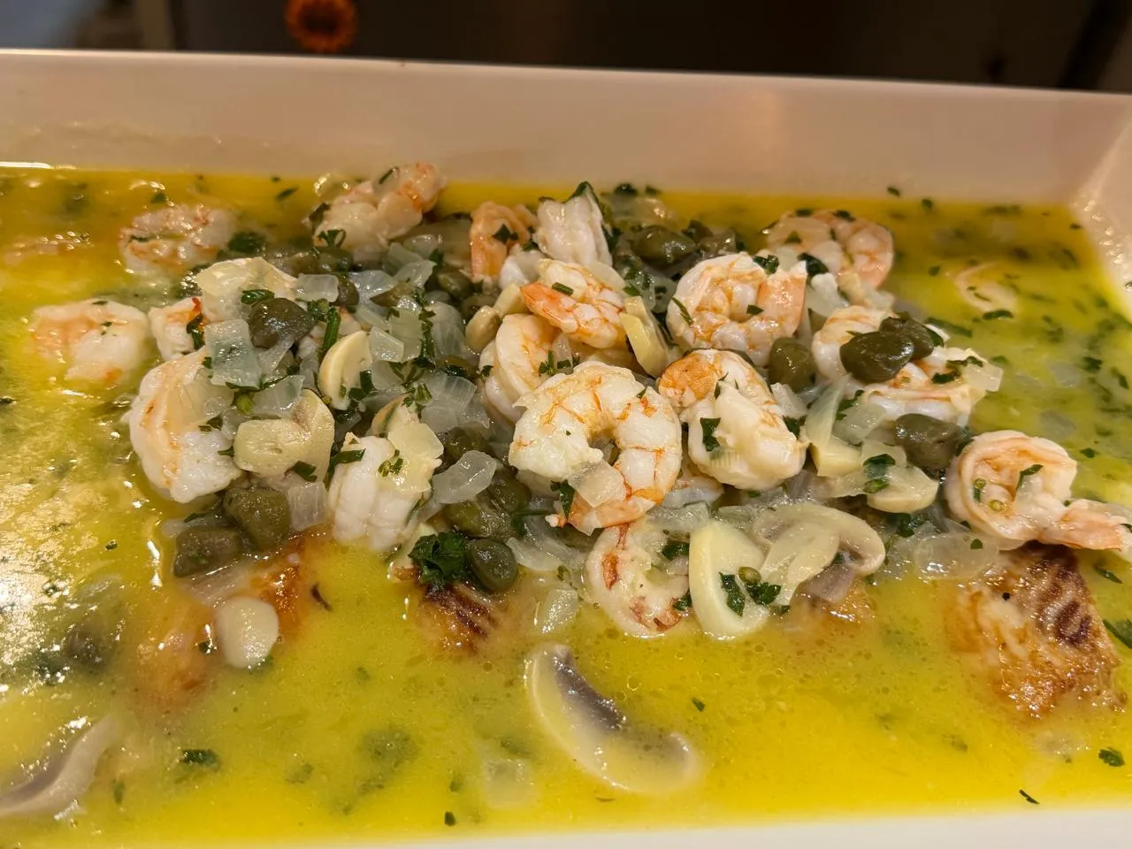Peixe com camarão — Filé de peixe coberto de camarões, alcaparras e manteiga