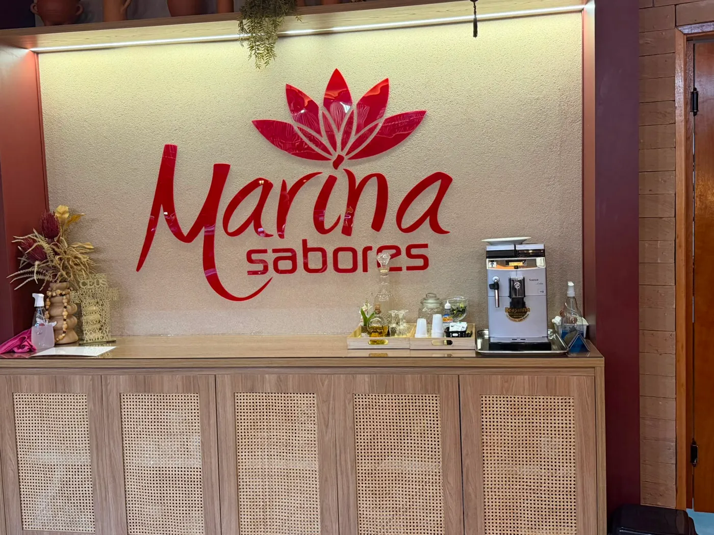 Recepção do Marina Sabores com o logotipo da casa em relevo na parede