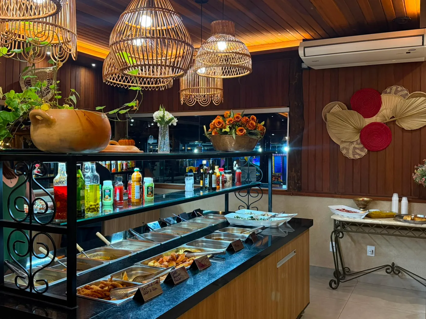 Salão do Marina Sabores com o balcão do buffet e luminárias de fibra natural